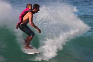 Cory Lopez surfs with his daughter on his back.
