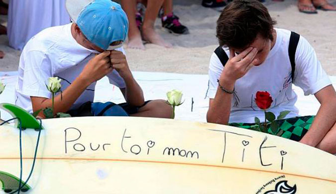 Two mourners sit next to a surfboard that reads "For you my Titi" during a march on April 15. Photo: AFP Two mourners sit next to a surfboard that reads "For you my Titi" during a march on April 15. Photo: AFP 