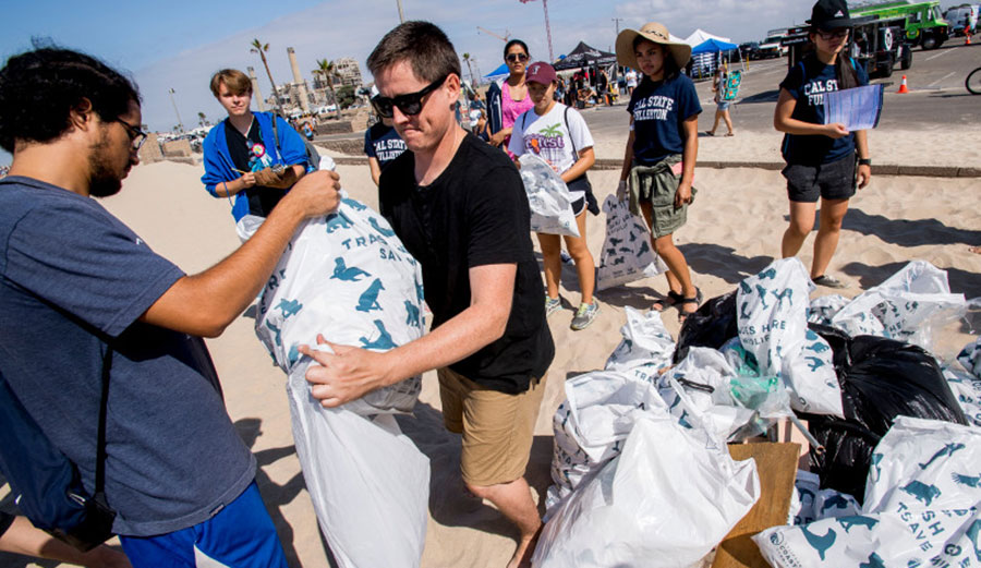 Andrew Sneddon, center, of Coastal Playground, accepts trash collected by volunteers during the California Coastal Cleanup Day at Huntington State Beach on Saturday, September 16, 2017.