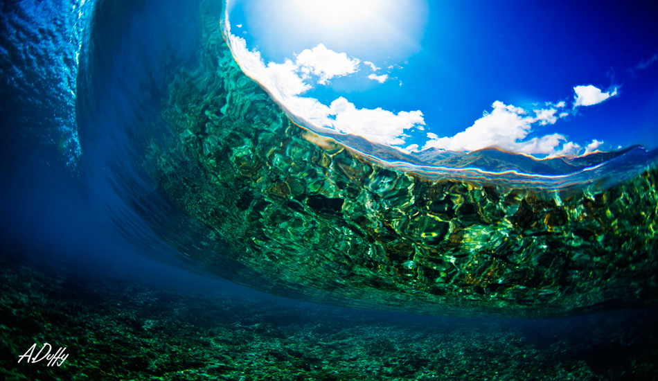 Underneath Teahupoo. I love how you can see the reflection of the reef and the mountains in the background. Photo: <a href=\"https://adamduffyphotography.com/\">Adam Duffy.</a>