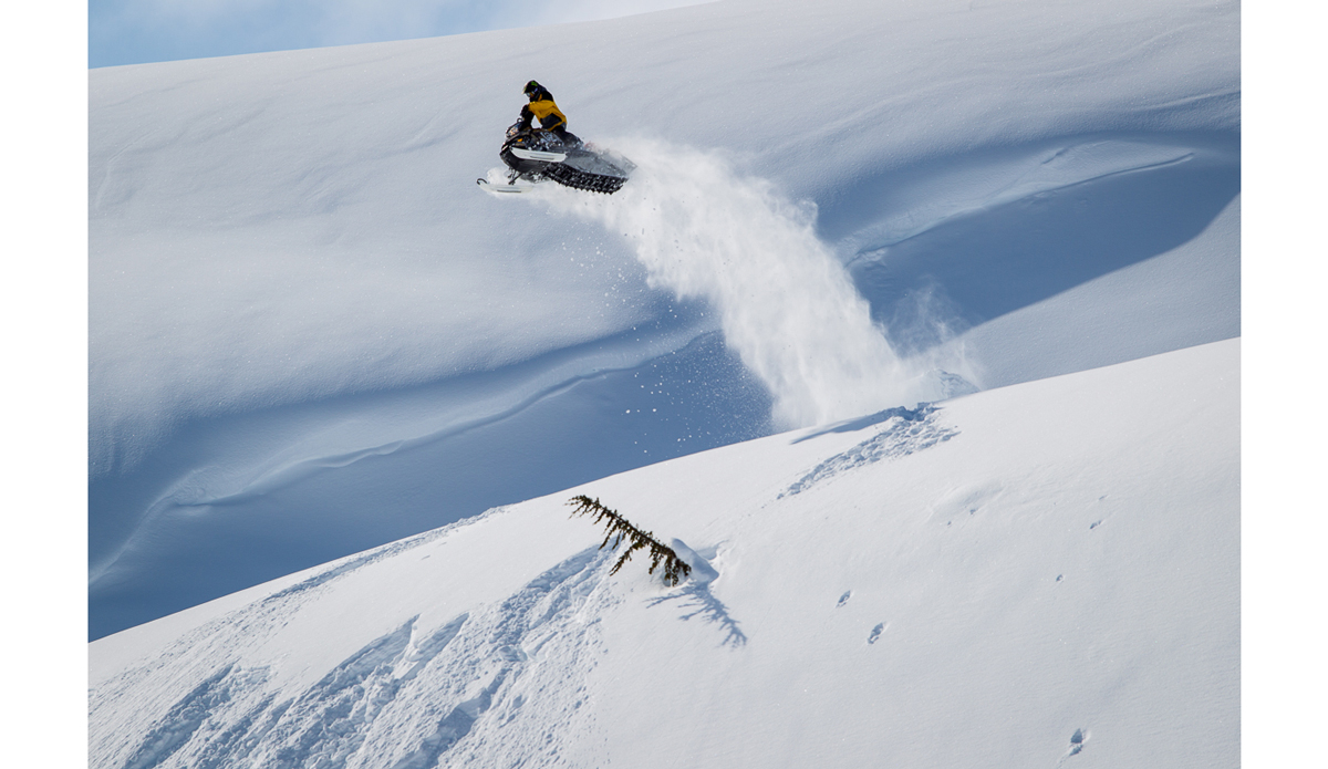 Mikey Rencz has been riding a snowmobile longer than most people have been snowboarding. He started filming in the backcountry with one when he was 16 years old so it feels like riding a bike to him.  This was the first time he decided to hit a snowboard jump on one though and he scared the shit out of us.  It took him 3 tries to land and each failed attempt he would ditch the sled 30 feet up and come crashing down.  The best part was after he stuck it he looked down and realized he was riding Jussi s sled.   2 days later Jussi’s suspension broke going down the trail. Photo: <a href=\"https://www.adammoran.com/\">Adam Moran</a>