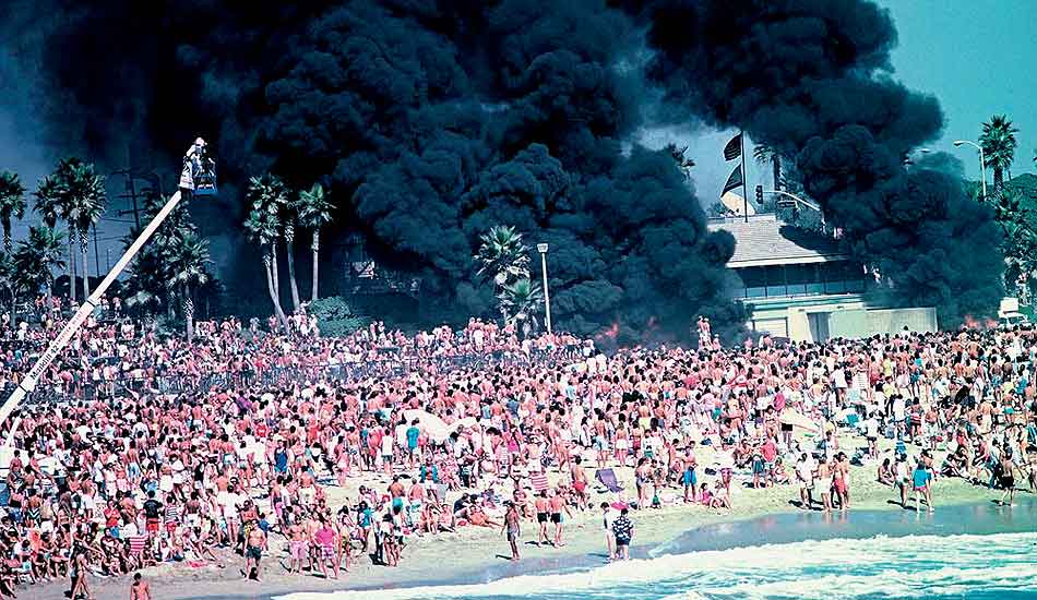 1989: On August 31, 1986, the OP Riots occurred in Huntington Beach, California. Riotous crowd members hurled bottles, drinks and sand at police officers then moved their uproarious behavior to the streets of Huntington Beach. Police cars, a lifeguard Jeep and an ambulance were set ablaze by flares found in police HQ by rioters. Clouds of black smoke billowed into the sky, signaling the day\'s destruction. As a result, the affair made front page news on the LA Times and Ian Cairns resigned from the ASP and returned to Australia. Photo courtesy of <a href=\"www.aspworldtour.com\">ASP</a>