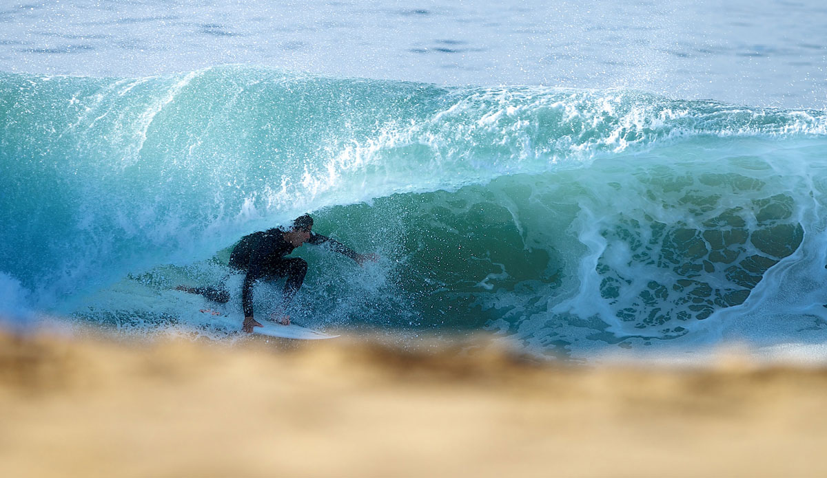 Teddy Navarro does his best to hide behind the lip of this heavy shore-breaking barrel and below the seven-foot tall wall of sand. Photo: <a href=\"https://www.driftwoodfoto.com/\">Benjamin Ginsberg</a>