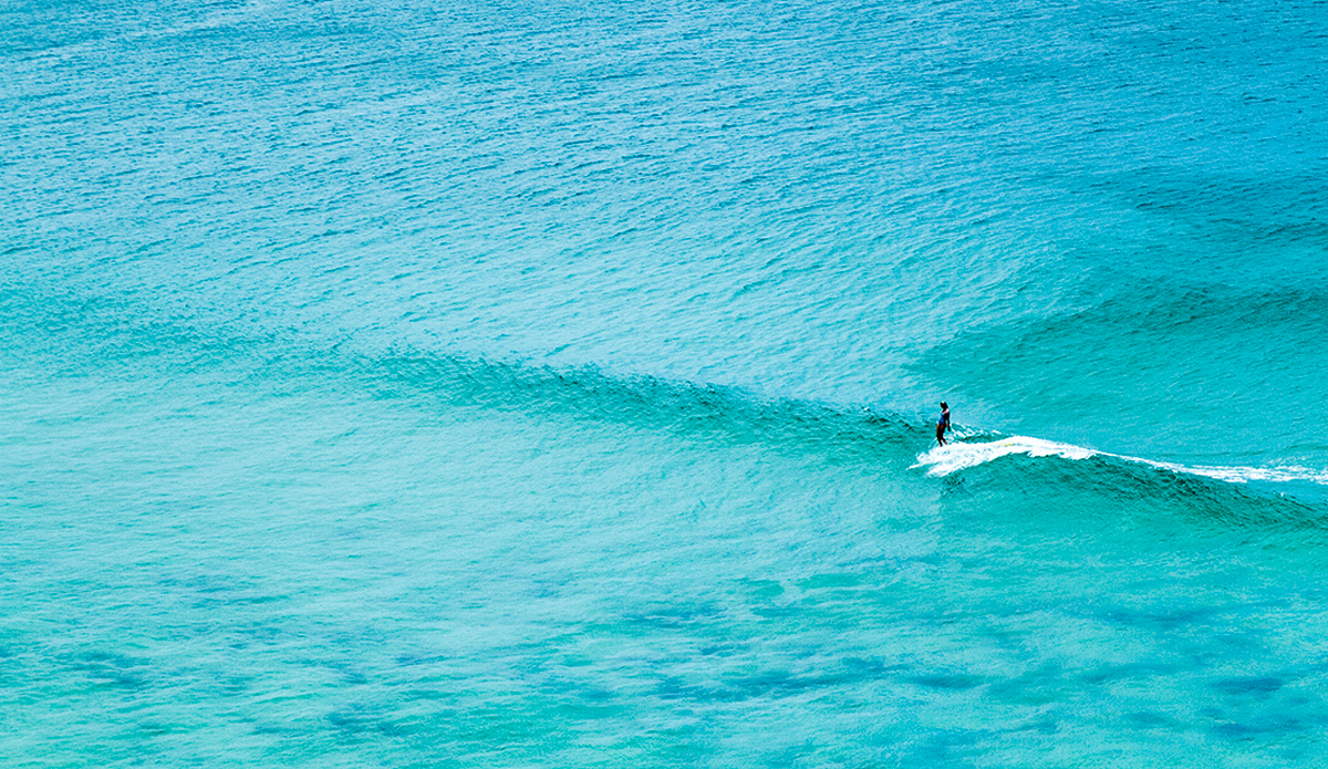 Ivy Thomas—Secret Spot, Australia. Some days are just unique. Ivy Thomas is like my little sister, and we do heaps of road trips up and down the coast in search of waves and cruisey days. On this particular day, we turned up at one of our favorite spots to find it virtually empty. The tide was extremely high, so it seemed the whole shortboard fraternity had ventured elsewhere, and we were left with long walled peelers, perfect for a log. This image is very reflective of Ivy herself. Simple pleasure. Simple beauty. Ivy is an incredibly positive human, she would smile and have a chat to the boogey man. I watched Ivy catch twenty or more waves in this solo session, and she kept looking up at me, grinning, sharing the joy she was having down in the water below. A wonderful memory. Photo: <a>Fran Miller</a>