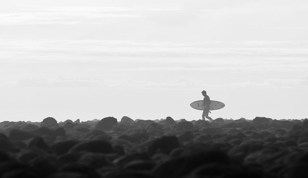 An unknown surfer heading out but first has to dance around a field of rocks at The Queen of the Coast, Rincon. Photo: <a href=\"https://www.kincaidcliffordphotography.com/\"> Brian Clifford</a>