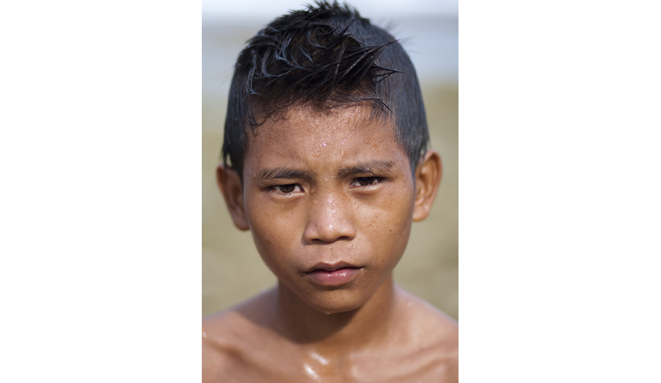 Lagundri Local. Many of the locals at Lagundri Bay, on Nias, have quite a bit of attitude. This young punk, around 8 years old, had all the genes of his warrior ancestors. He\'ll be one of the pack leaders out at Lagundri within a couple of years, and woe to any who drop in on him then. It\'s always a pleasure to shoot Indonesians, they actually love being photographed which makes life very easy for photographers. Image: <a href=\"https://www.sparkesphoto.com\" target=\"_blank\">Sparkes</a>
