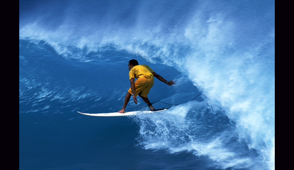 February 2001 - Streaking across the wall of a bright blue Caribbean wave, Puerto Rican Gammalier Jorge provides interesting contrast with his yellow boardshorts and t-shirt. Image: <a href=\"https://stevefitzpatrick.com/\" target=\"_blank\">Fitzpatrick</a>  
