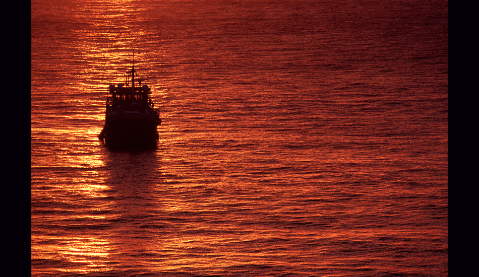December 2004 - As the Quiksilver Crossing rests at anchor in Aguadilla Bay, Puerto Rico, the setting sun lights up a fire on the water. Image: <a href=\"https://stevefitzpatrick.com/\" target=\"_blank\">Fitzpatrick</a>  