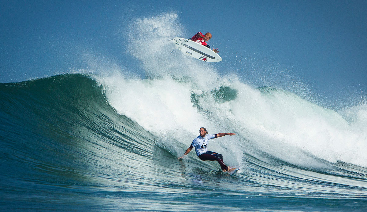 Kelly Slater of Florida, USA (pictured RED) performs an aerial manuever behind Matt Wilkinson of Australia (pictured WHITE) during Round 1 of the Quiksilver Pro France. Wilkinson defeated Slater and advanced into Round 3 while Slater will surf again in Round 2. Photo: <a href=\"https://www.aspworldtour.com/\">ASP</a>/ Poullenot