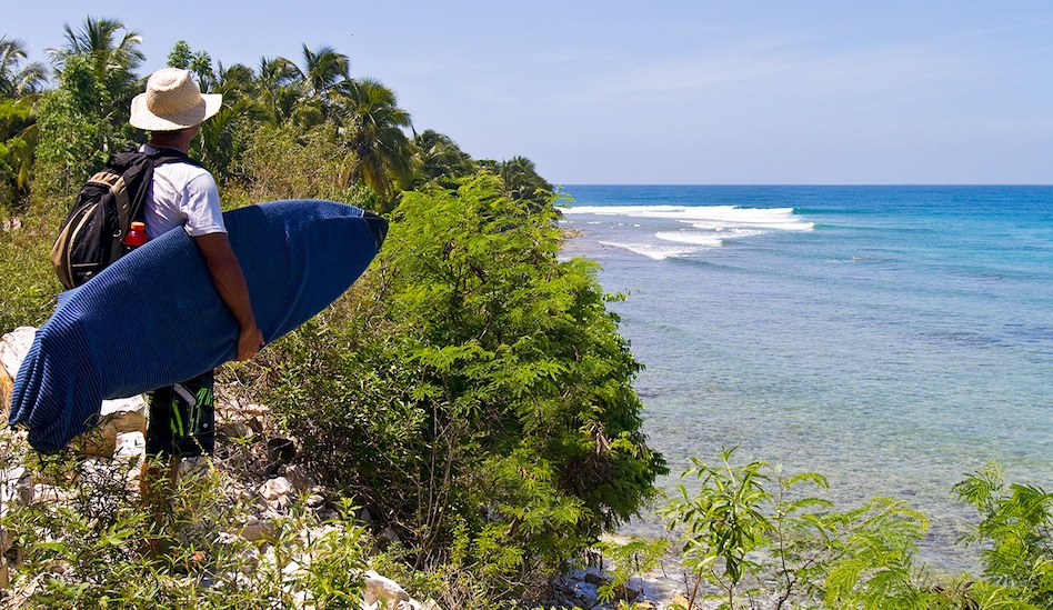 The limestone cliffs and left point setup may look like Indonesia, but it\'s Haiti in the Caribbean Sea. Emi Cataldi checks a new lineup near Aquin.  Photo: John Seaton Callahan

