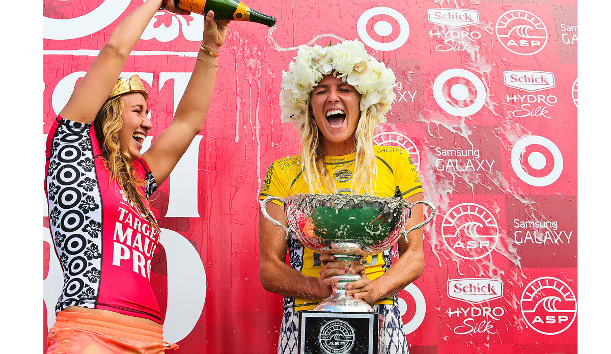 Stephanie Gilmore of Tweed Head, NSW, Australia (pictured yellow) celebrates her sixth ASP World Title victory as outgoing ASP World Champion and recently crowned Target Maui Pro Champion Carissa Moore (HAW) douces her in champagne during the awards presentation at Honolua Bay Maui on the 27 November 2014. Photo: <a href=\"https://www.aspworldtour.com/\">ASP/Masurel