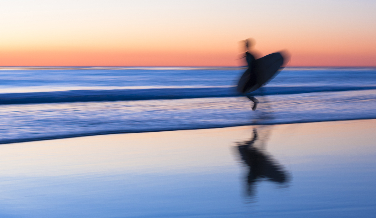 A surfer races to sneak a few waves before dark. Photo: <a href=\"https://www.LucarelliPhoto.com/\"> John Lucarelli</a>