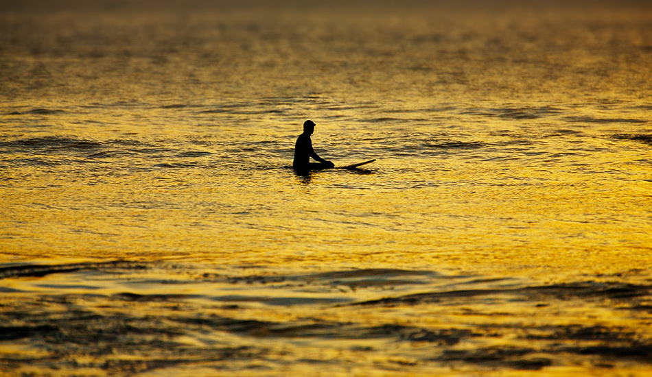 A lonely surfer waits for \'One More Wave\' during a warm golden sunset at Gwithian beach in Cornwall. Photo: <a href=\"https://www.jordanweeks.com/\" target=_blank>Jordan Weeks</a>