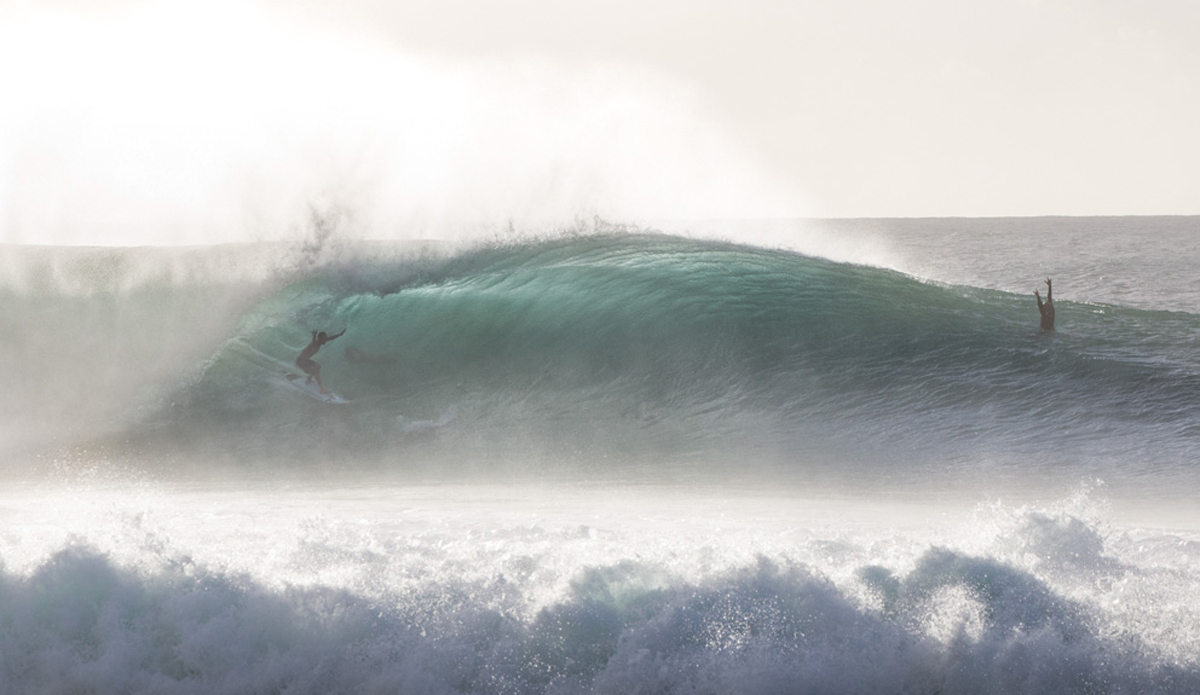 Two surfers sharing the thrill of getting barreled at pipe.