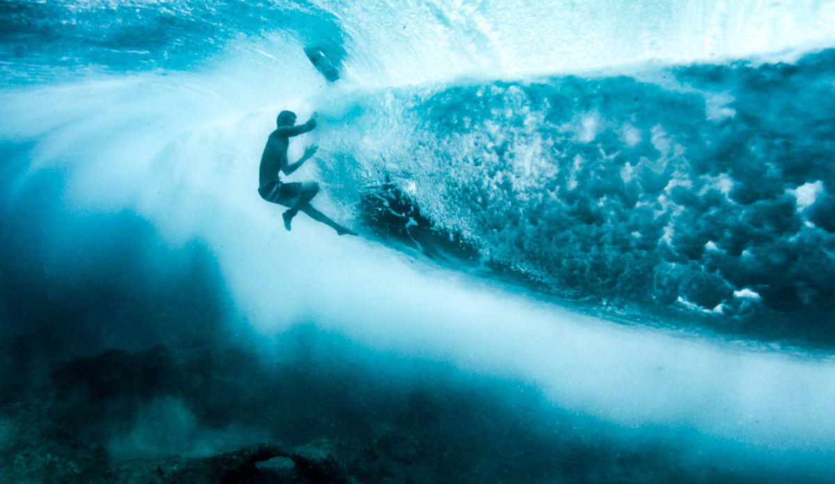 A surfer shooting a kamehameha blast while diving a wave.