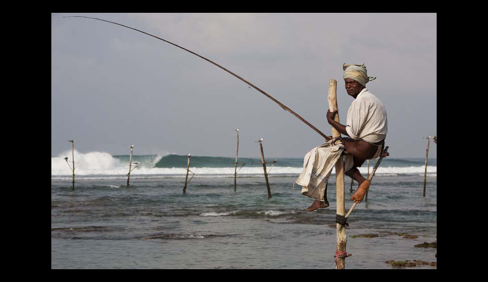 SOMEWHERE IN SRI LANKA. 
A typical fisherman with a perfect left reeling behind him. Photo: <a href=\"https://www.luciagriggi.com\" target=\"_blank\">Lucia Griggi</a>