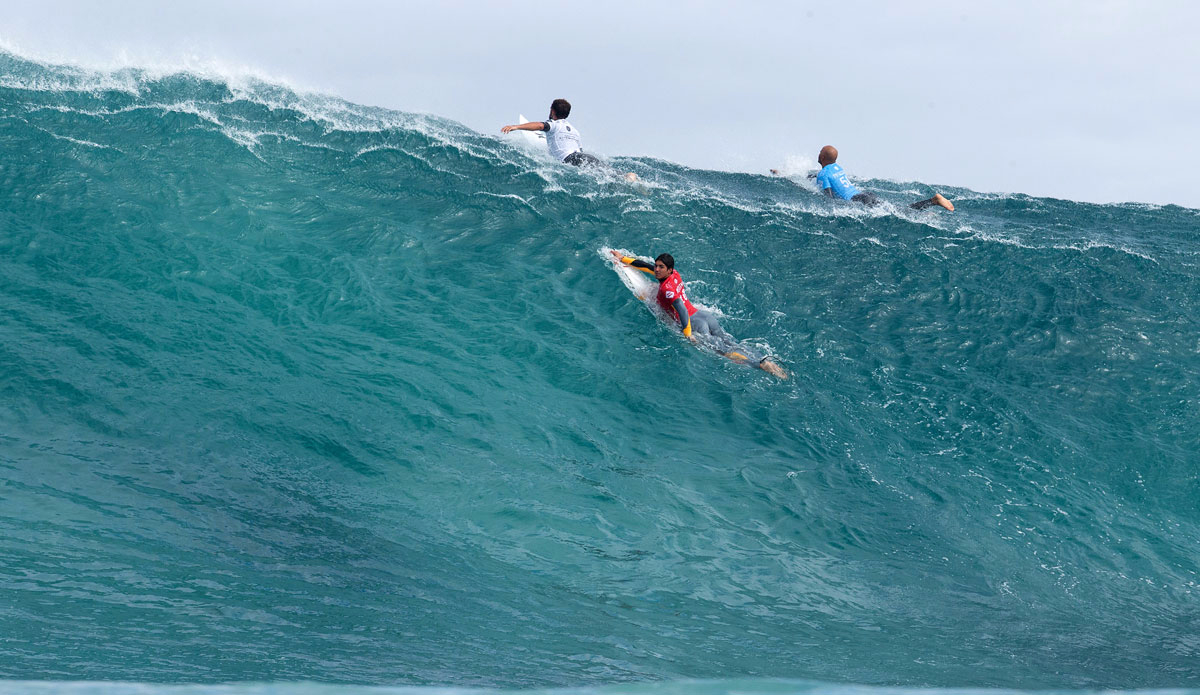 Gabriel Medina (red) of Brasil, Alejo Muniz (white) of Brasil and Fred Patacchia (blue) of Hawaii (pictured) paddling hard to scratch over the top of a large wave at The Box during round 1 of the Drug Aware Margaret River Pro. Photo: <a href=\"https://www.worldsurfleague.com/\">WSL</a>/<a href=\"https://www.kellycestari.com/\">Cestari</a>