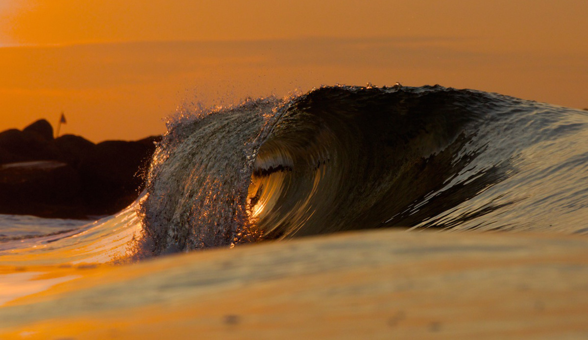 Another one from that early morning swim in mid-July.  I really like how the lip of the wave is just spilling over and the barrel is lit up orange.  I have larded that glassy conditions are key to grabbing these kinds of shots.  What I really like about this one is that the wave is actually pretty small but the detail is so intriguing. Photo: <a href=\"https://www.mgvphotography.com/\">Michael Vericker</a>