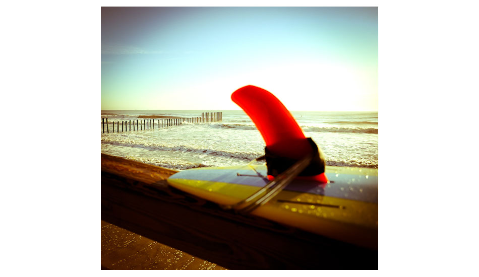 This is The Poles. Same as in picture 14. The name was given by the poles that separate a navy installation and a city park. Being just a little over a mile from my house, this is my go to spot to check the surf. Hanging out talking to people about the swell, this guy put his board on the rail and the red fin just really stuck out to me. Photo: <a href=\"https://www.marksainwilson.com/?splash=1\" target=_blank>Mark Wilson</a>
