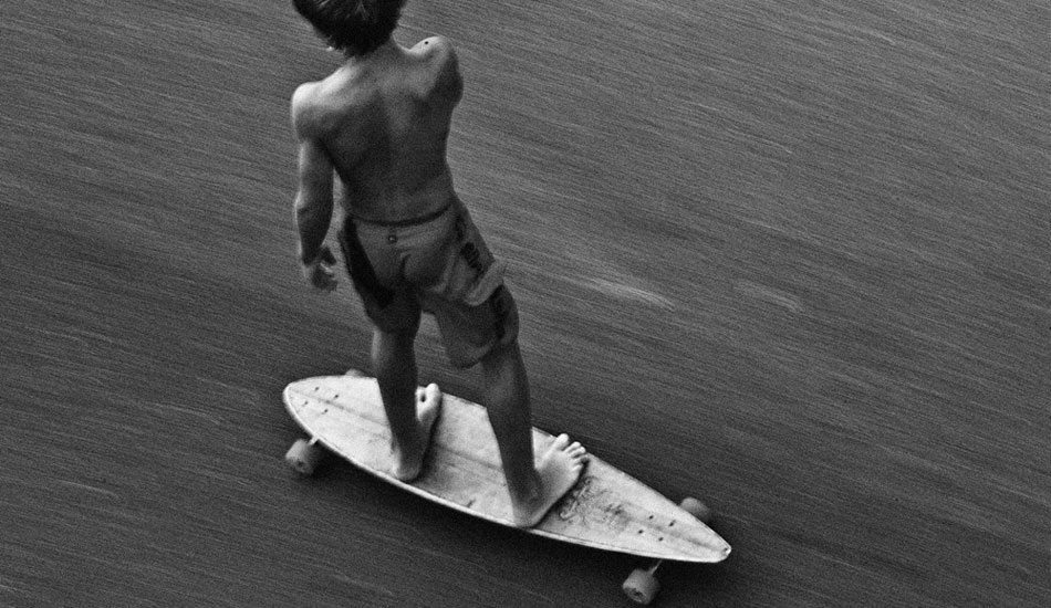 Man, this is the ultimate grommet just flying down the road that runs next to the Quiksilver Pro. I was staying in a hotel that overlooked the comp site and noticed this kid pegging down the hill and basically the only camera near me was my 600f4 so i grabbed it turned it on not knowing what the setting was and just belted out a big seq, and this one was rad. Still have no idea who he is. I would love to give him a print one day. It\'s just one of those shots. Maybe I\'ll never know, but that\'s half the beauty, I guess. Photo: <a href=\"https://www.natesmithphoto.com/\" target=_blank>Nate Smth</a>