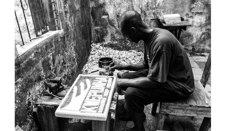 Local craftsman and wood carver, Isaac Mitlon, puts the finishing touches on the Kwepunha Retreat sign carved out of wood from the rainforest. Photo: Sean Brody