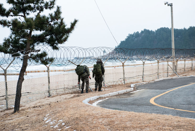 Two soldiers patrol the fence for changes or damage just south of 38th Beach at dusk. Photo: <a href=\"https://www.shannonaston.com/\" target=_blank>Shannon Aston</a>.