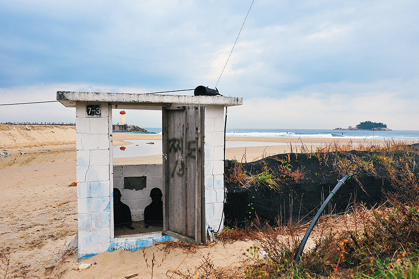 An aging decoy guard station for the ROK (Republic of Korea) army seen here as the dropping swell trickles across the bank and some punters get the last of it on a Sunday morning. Photo: <a href=\"https://www.shannonaston.com/\" target=_blank>Shannon Aston</a>.