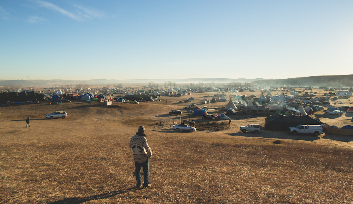 Sunrise revealed a haze filled campground even larger than we anticipated. Tents, structures, teepees, and smoldering smoke from the previous nights fires filled the air. Photo: Keegan Gibbs