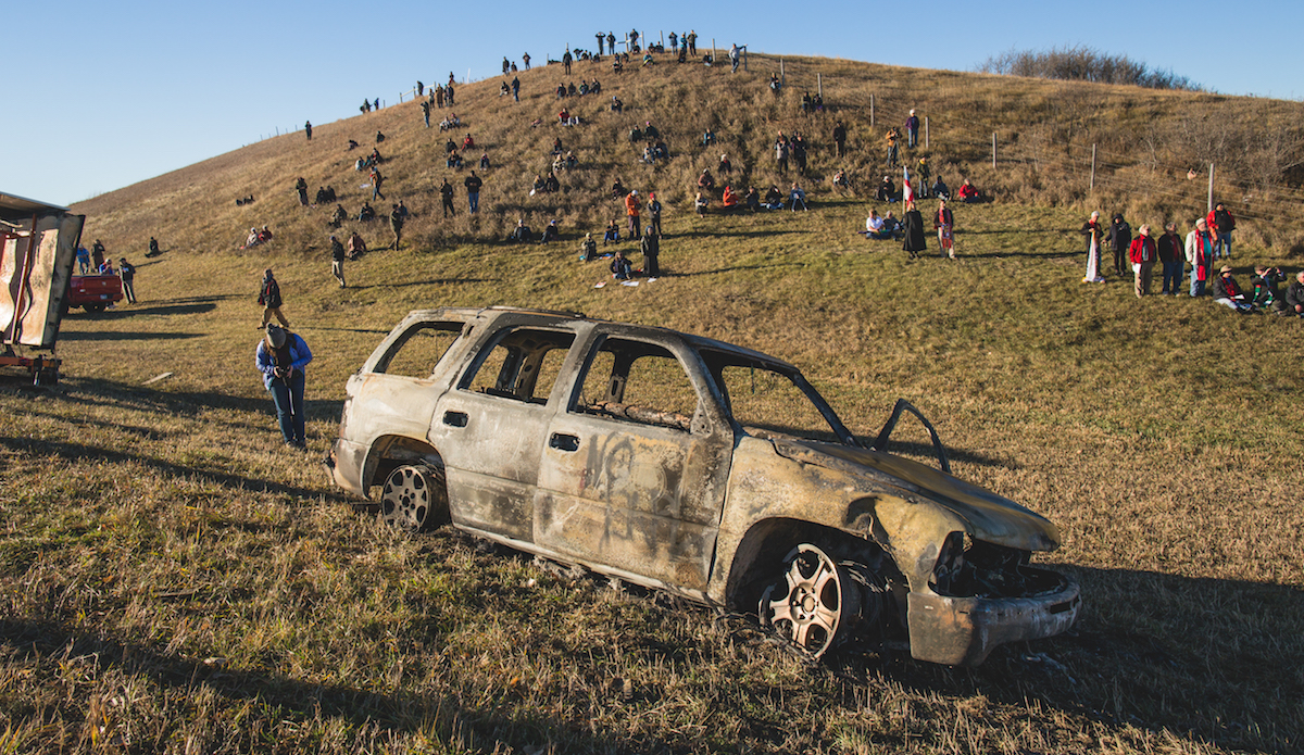 Kamalei standing in front of a burned out military road block on the bridge that separates the Pretest camp from the construction site. Photo: Keegan Gibbs