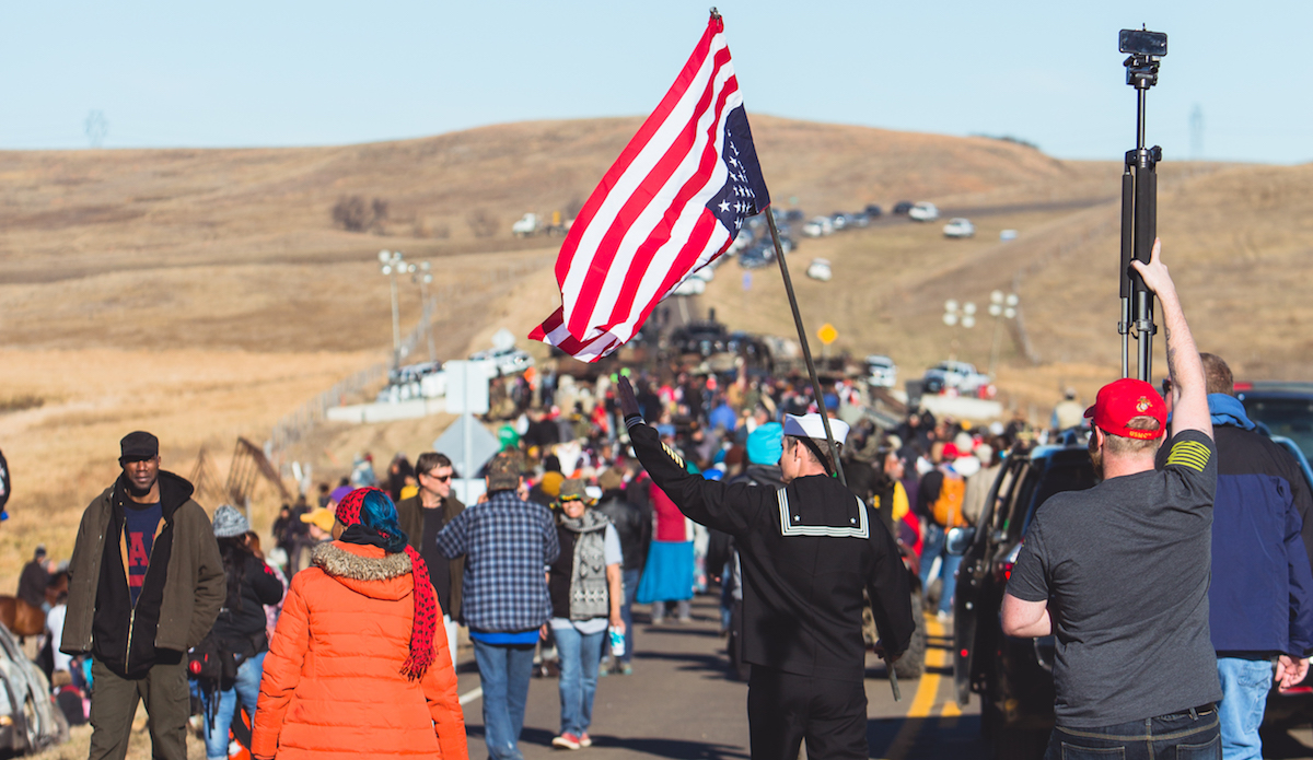 U.S. Navy veteran, Petty Officer 1st Class Kash Jackson, came to North Dakota to uphold the Constitution by protecting the American citizens he swore to defend. By flying the flag upside down, it signals distress, which he associates with the natives struggle with over militarized police acting on behalf of corporate interests. He is quoted as saying “Our greatest enemies are not overseas, our greatest enemies are right here.” Photo: Keegan Gibbs