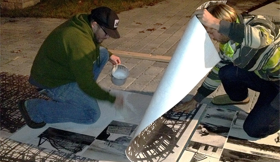 Glueing photos down to the 5 sheets of Plywood -
The base of the mural was made up of black and white photos I\'ve taken over the years in NJ. The mural was to be painted live in one day so this was prepped before hand to save time