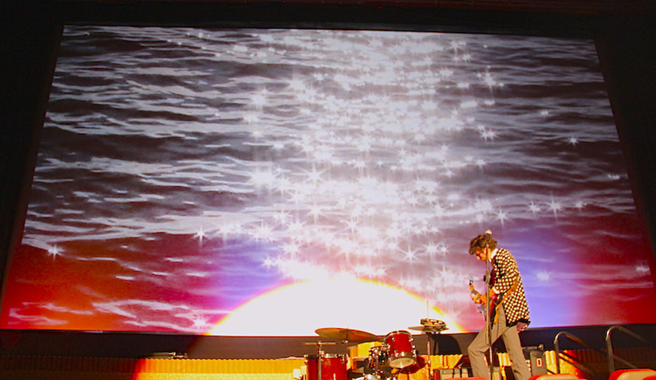 Guy again, in front of the big screen. Photo: <a href=\"https://www.savethewaves.org\">Save the Waves</a>