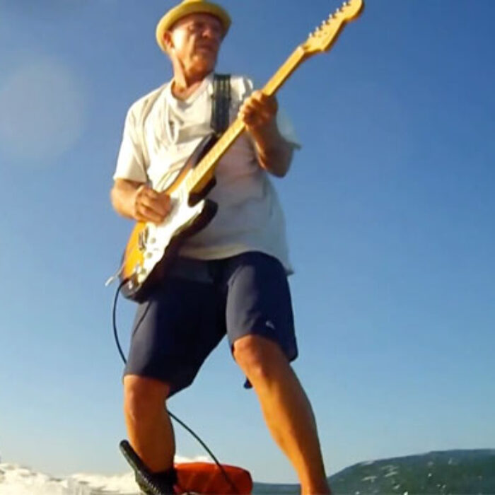 Guy playing guitar while surfing.