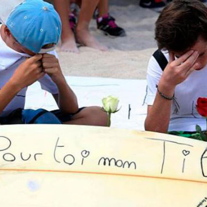Two mourners sit next to a surfboard that reads "For you my Titi" during a march on April 15. Photo: AFP Two mourners sit next to a surfboard that reads "For you my Titi" during a march on April 15. Photo: AFP