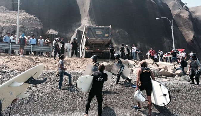 Surfers trying to stop dump trucks from unloading boulders onto the beach.