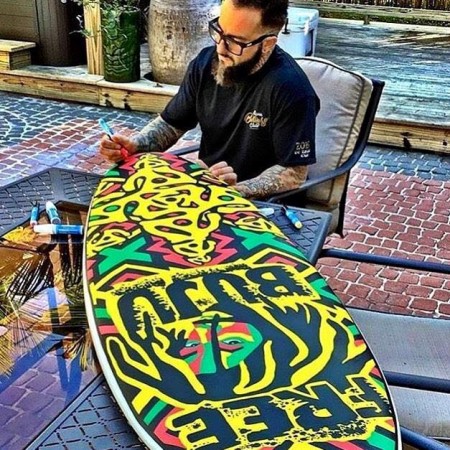 ark Longenecker puts finishing touches on the free-hand painted surfboard raffled off at Dub Massive 2016 benefiting Surfers For Autism.