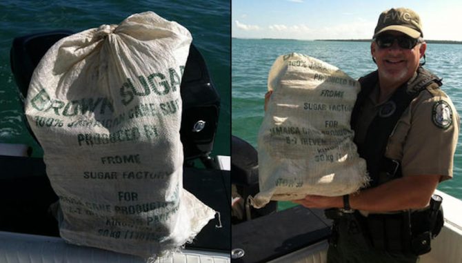 Florida Fish and Wildlife Commission officer, Bobby Dube, poses with a bag of floating marijuana found floating just offshore of the Keys. Photo: FWC
