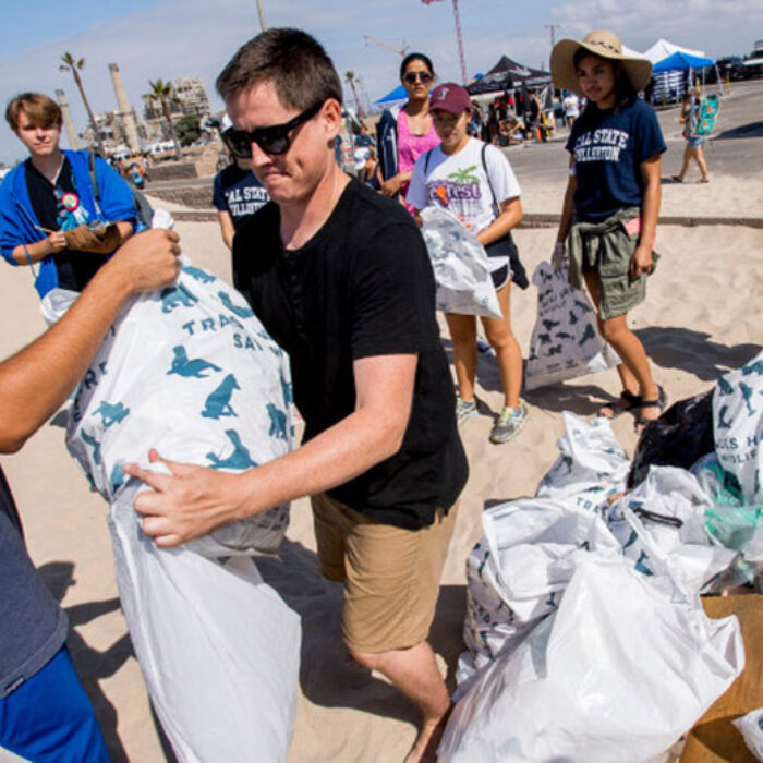 Andrew Sneddon, center, of Coastal Playground, accepts trash collected by volunteers during the California Coastal Cleanup Day at Huntington State Beach on Saturday, September 16, 2017.