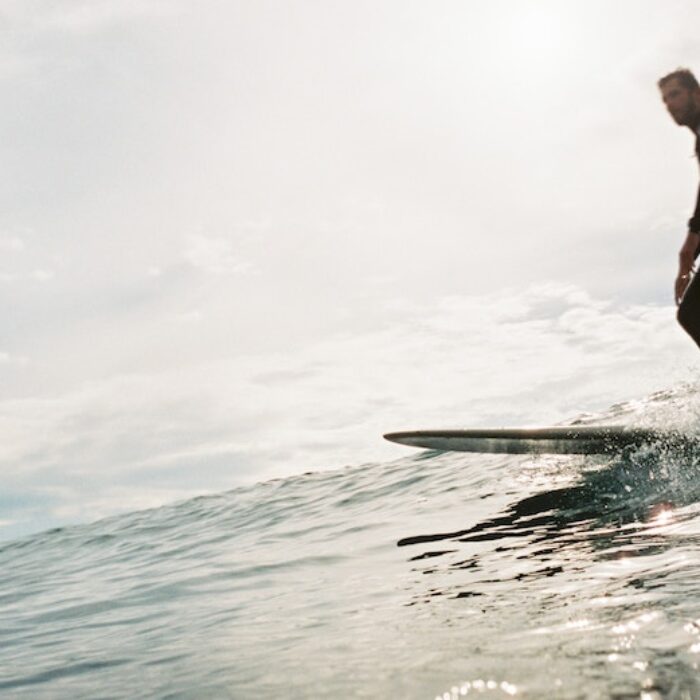 A surfer skims along on a longboard.