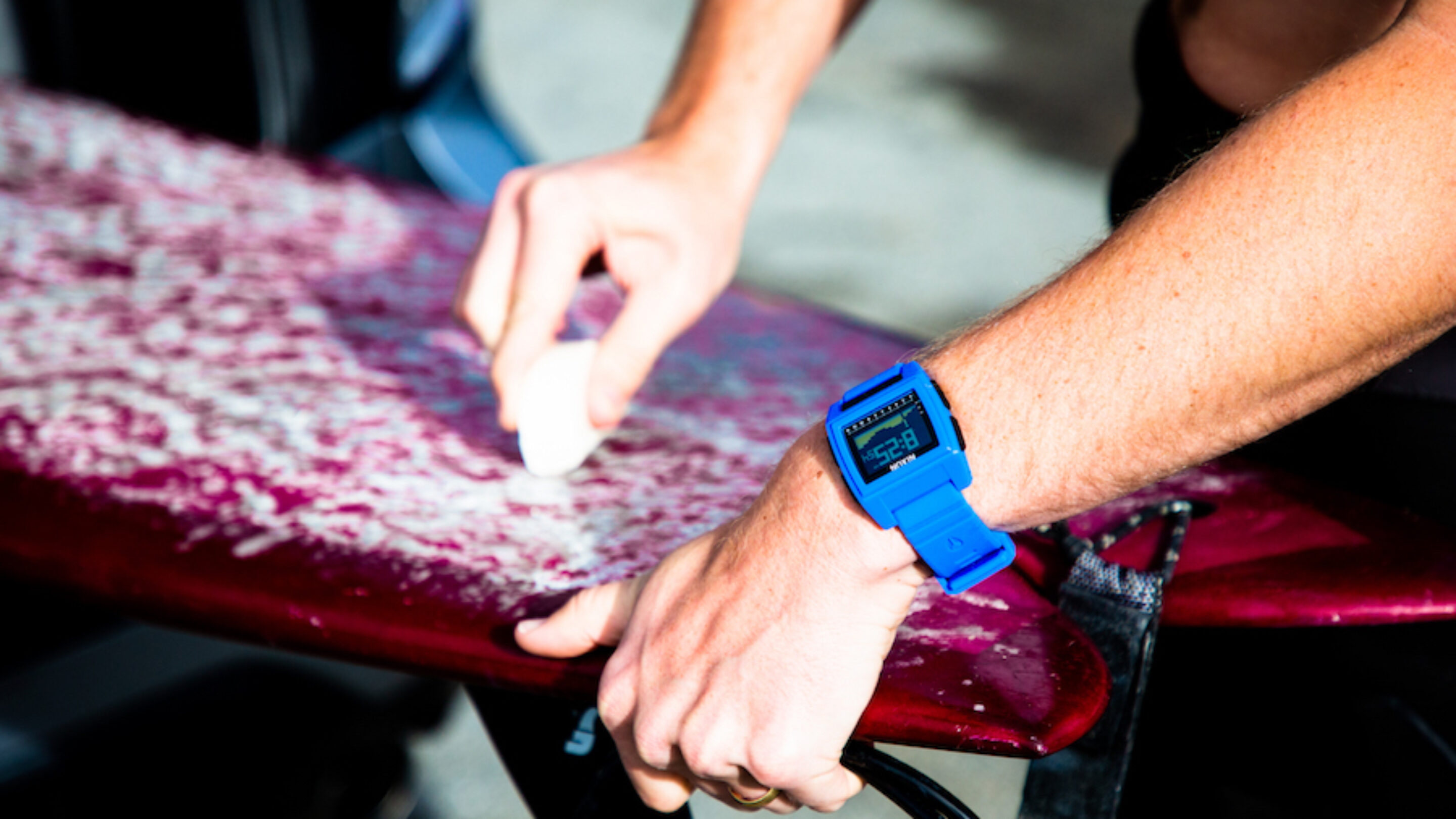 The Nixon Base Tide Pro applying surf wax