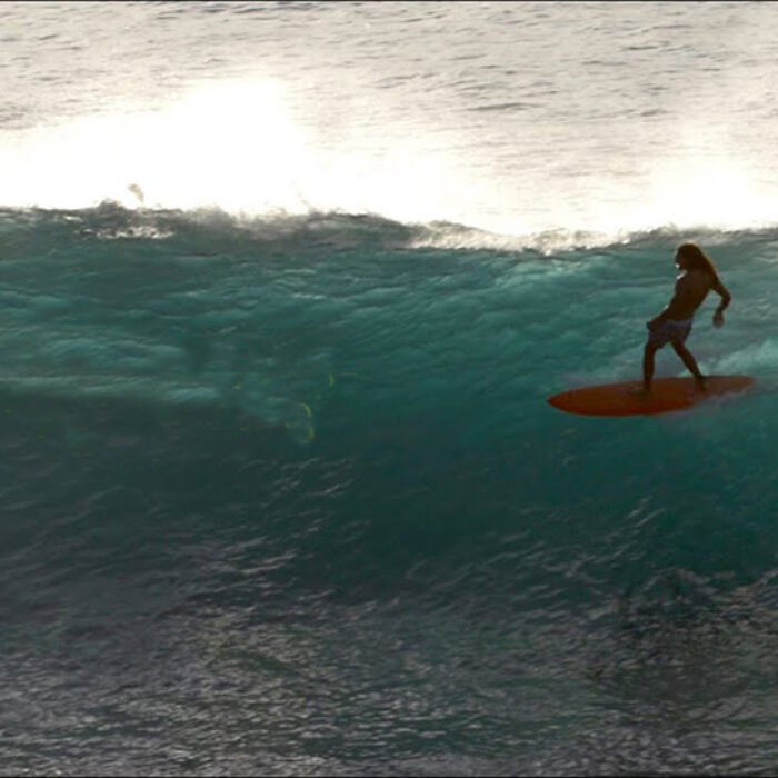 Surfer rides mid-length surfboard on big wave