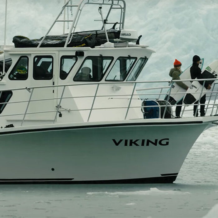 Surfers on boat in Alaska with surfboards