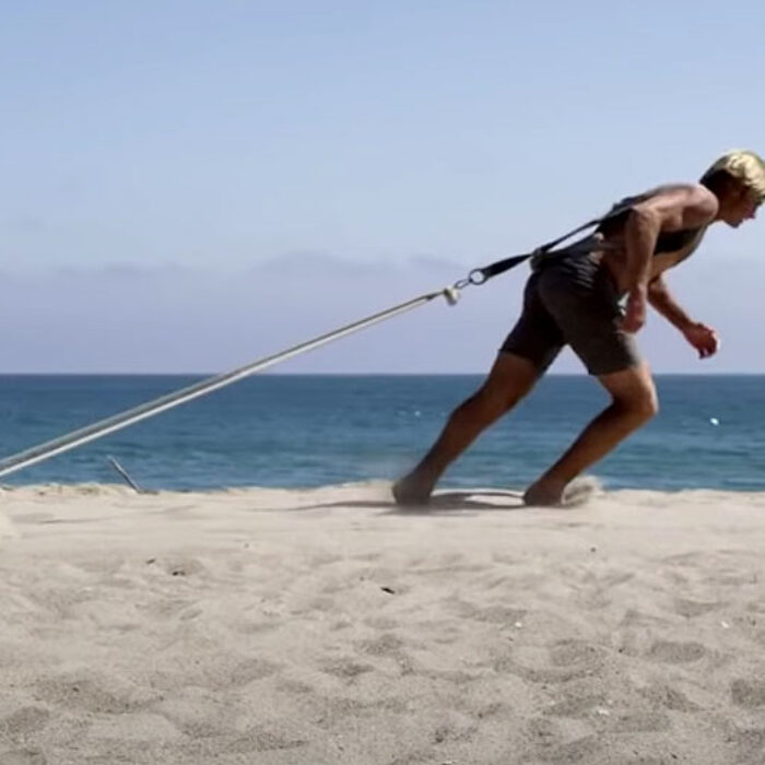 Laird Hamilton draggin a log through the sand