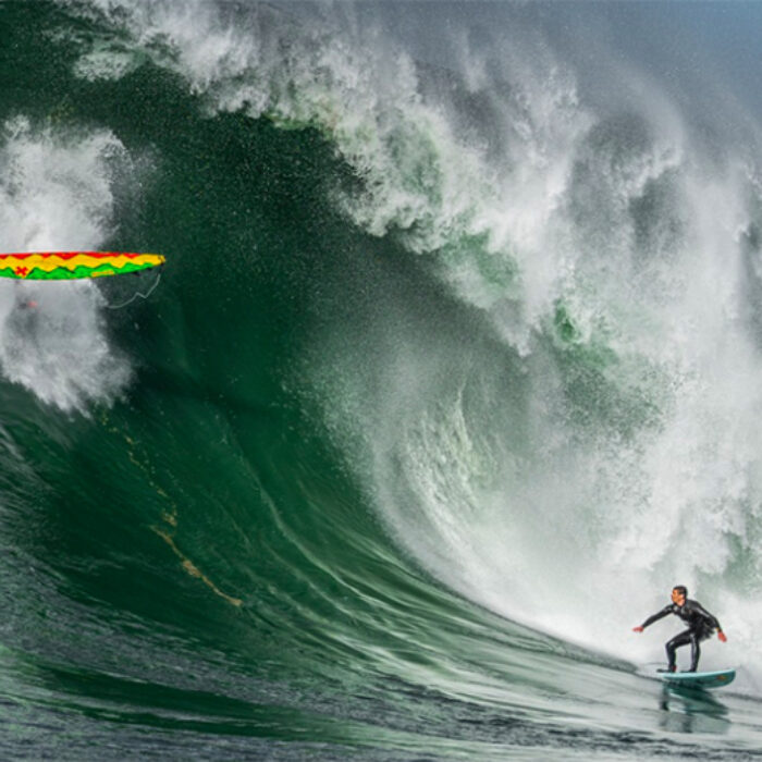 Ian Walsh on a giant wave at Mavericks as a surfboard falls from the lip