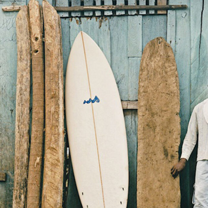 A surfer stands next to traditional boards in africa