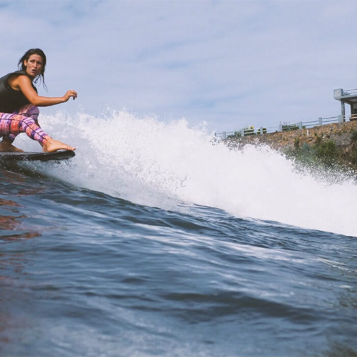 Kassia Meador riding a wave on a longboard