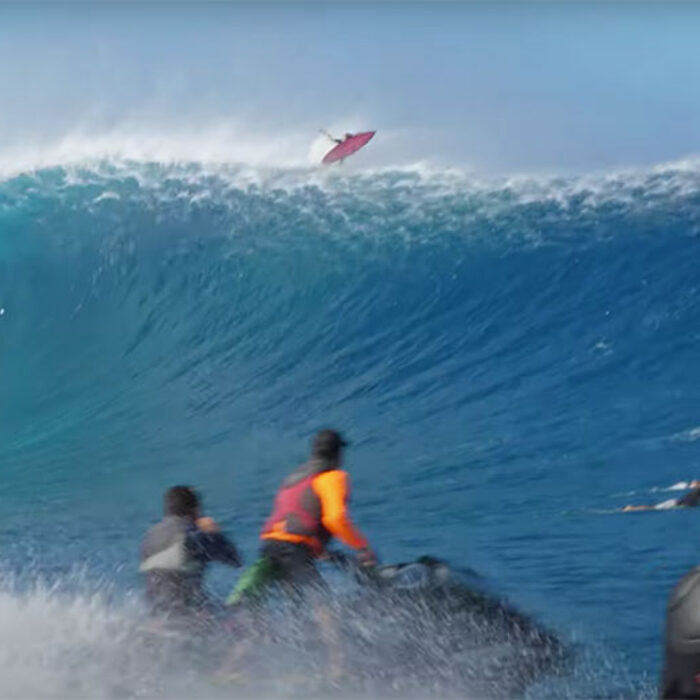 Surfers in Hawaii running from huge wave