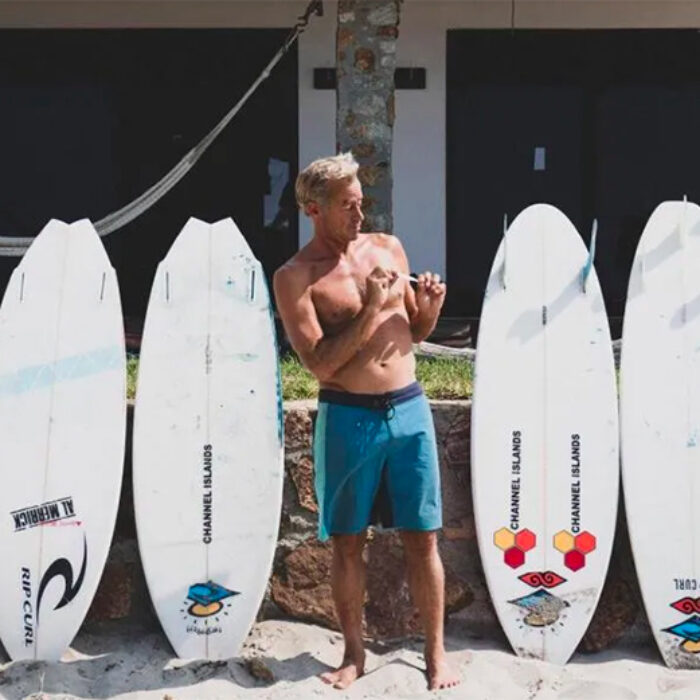 Tom Curren stands in front of his surfboard quiver