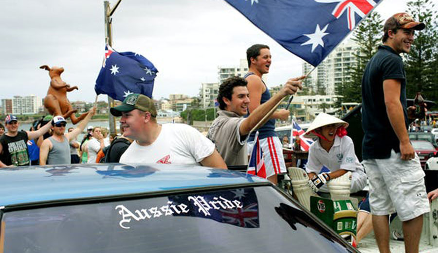 Youths wave Australian flags to passersby at Cronulla Beach in Sydney
