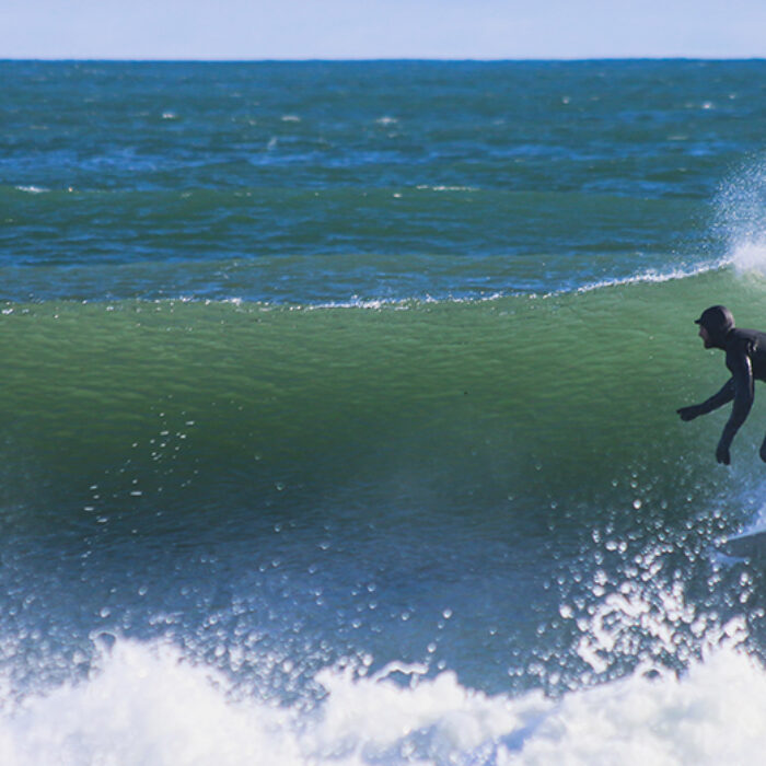 a man winter surfs in a full wetsuit